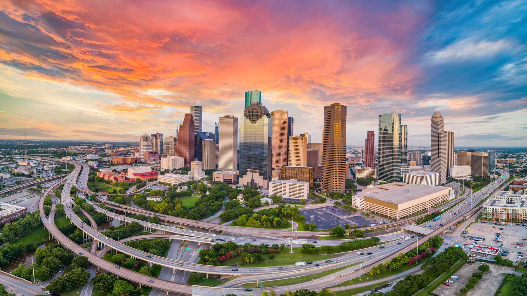 Houston skyline at sunset above a sprawling highway interchange